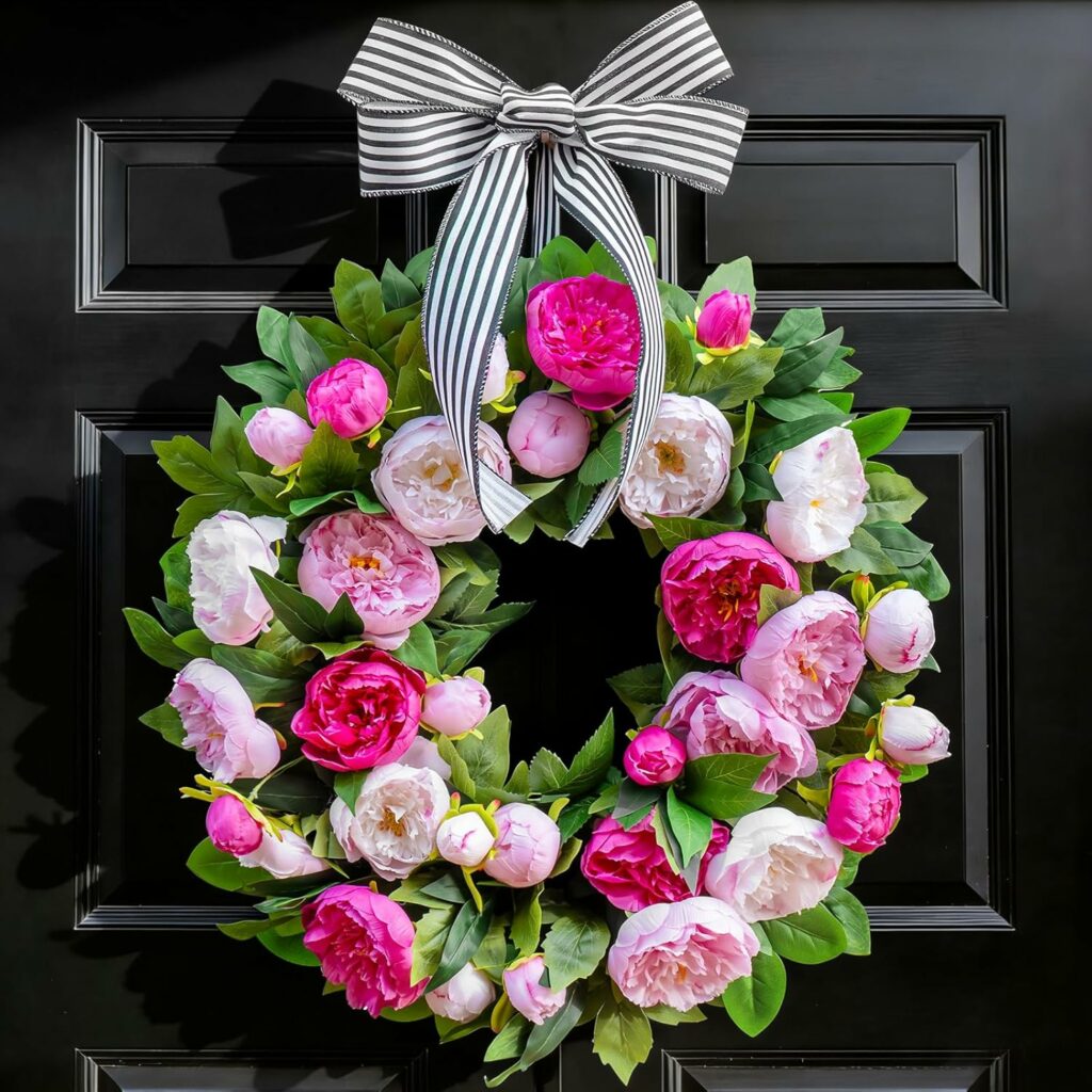 Spring wreath with pink and white peonies and black and white striped ribbon hanging on front door